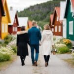 A couple går hånd i hånd gennem en charmerende svensk landsby omgivet af farverige træhuse og blomstrende blomster